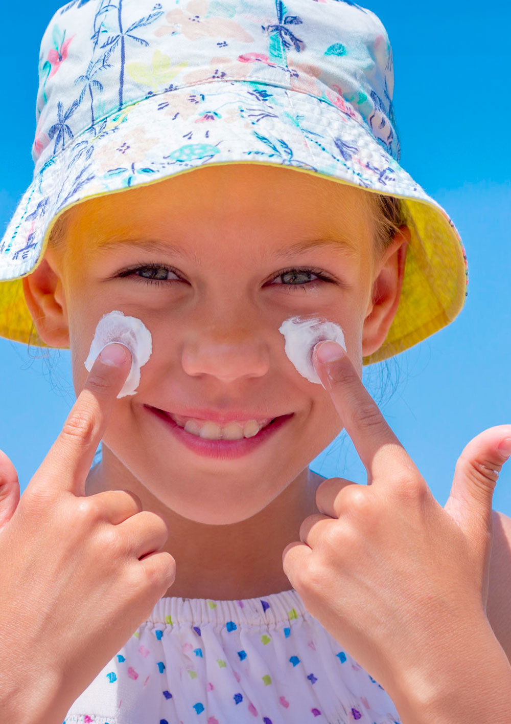 Happy girl applying sunscreen